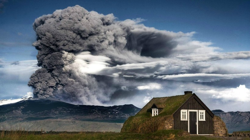 На фото: традиционный исландский дерновый дом на фоне вулкана Эйяфьятлайокудль