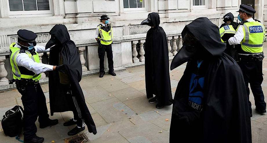 Фото дня: полицейские обыскивают протестующих, одетых в костюмы чумного доктора